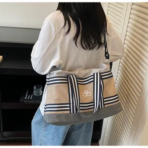 Detail of multi-color canvas travel bag with striped handles and bicycle logo embroidery