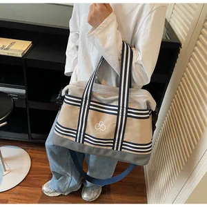 Macro view of canvas tote travel bag featuring striped handles and embroidered logo