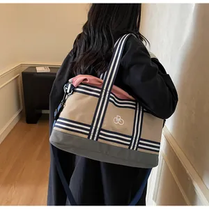 Detail of canvas travel bag with blue striped handles and beige gray color blocking