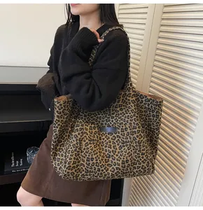 Detailed view of leopard print canvas tote bag featuring a large front pocket with black tag
