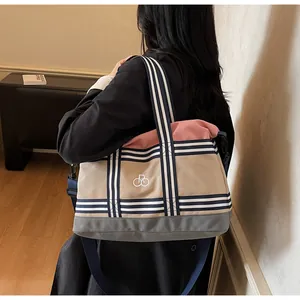 Three-color patchwork canvas tote bag with striped straps shown on a model's shoulder