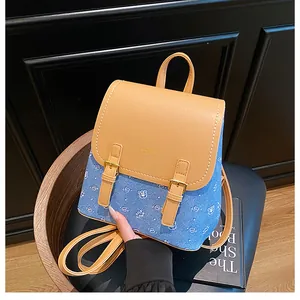 Detail of blue denim mini backpack with white bear prints and brown leather flap