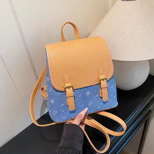 Detail of PU leather flap and blue denim body with bear pattern and gold buckles