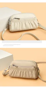 Macro detail of pleated leather crossbody bags in cream and beige with silver zippers
