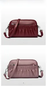 Close-up of pleated leather crossbody shell bags in fuchsia and purple with silver zippers