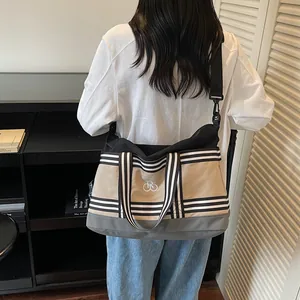 Large color-block canvas travel bag with adjustable strap and minimalist logo on shoulder