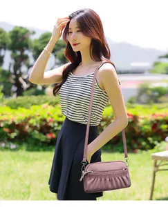 Detail of soft leather crossbody bag featuring three-layer zipper and pleated design