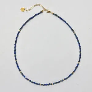 Detail of beaded necklace with blue natural stones and gold-plated heart charm