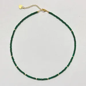 Macro view of green beaded necklace with 18k gold plated clasp and heart tag