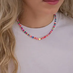 Collana di perle Heishi colorate con ciondolo a cuore dorato indossata su una maglietta