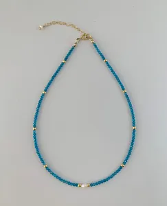 Details einer blauen Perlenkette mit weißer Perle und goldener Karabinerverschluss-Kette
