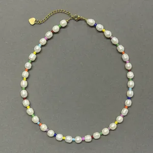 Detail of colorful beads and baroque pearls necklace with golden heart pendant