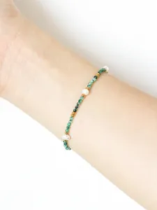 Dettaglio di un bracciale con pietre verdi sfaccettate e perle d'acqua dolce bianche