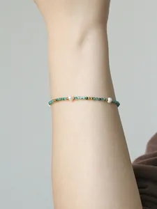 Dettaglio di un bracciale con pietre naturali verdi e perle d'acqua dolce sul polso