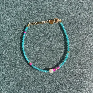 Bracelet artisanal avec pierres naturelles colorées et perle d'eau douce sur fond de pierre