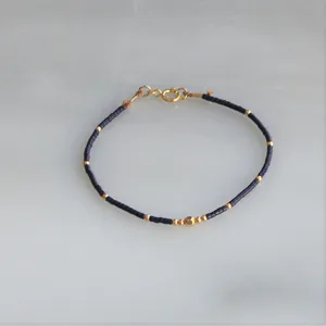 Detail of handmade beaded bracelet with dark blue beads and gold spring ring clasp