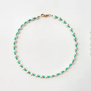 Detail of freshwater pearl necklace with turquoise beads and gold lobster clasp