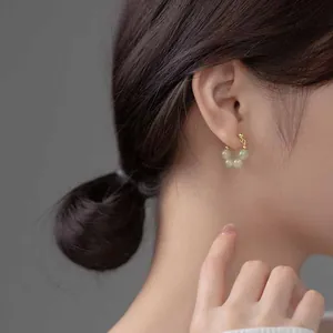 Elegant gold earrings with natural green stones worn by model in a profile view
