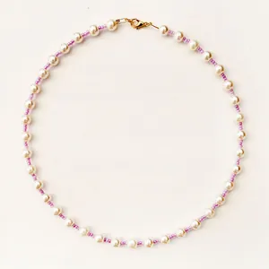 Close-up of pearl and purple bead necklace with a gold lobster clasp fastener