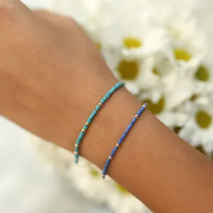 Close-up of bohemian turquoise and navy beaded bracelets with gold accents on wrist