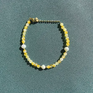 Bracelet fait main avec perles d'agate jaune et perles d'eau douce sur fond vert foncé