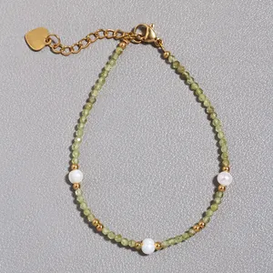 Dettaglio di bracciale con pietre verdi, perle d'acqua dolce e ciondolo a forma di cuore