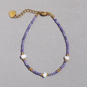 Macro scatto di braccialetto di perle viola con accenti dorati e perle barocche