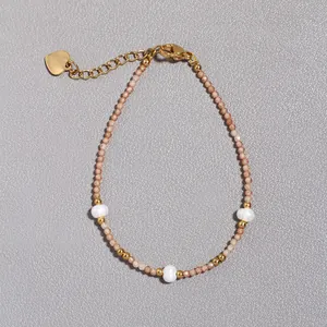 Dettaglio del bracciale con perle d'acqua dolce, pietre verdi e ciondolo a cuore oro