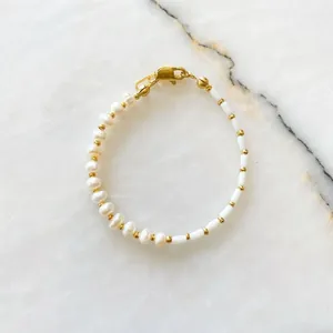 Detail of freshwater pearls and white tube beads bracelet on white marble surface