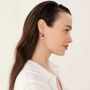 Detail of bohemian gold earrings featuring white pearl and colorful beads on a model