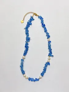 Détail macro de perles d'eau douce et pierres bleues sur une chaîne dorée
