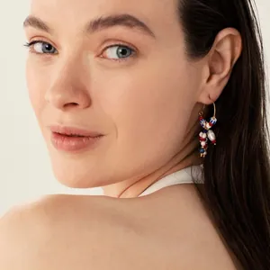 Detail of 18K gold-plated hoop earrings with colorful beads on a model's ear