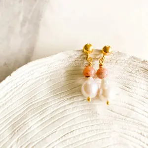 Macro shot of gold hoop earrings with pink beads and natural baroque pearl drops
