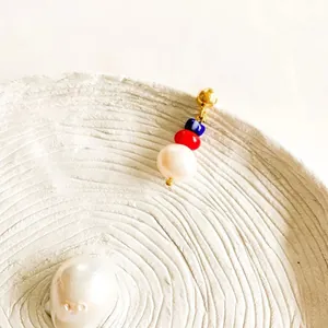 Detail of 18K gold-plated beaded drop earring with white pearl and colorful glass beads