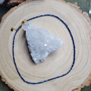 Macro detail of fine blue faceted stone beads with gold lobster clasp on wood display