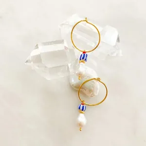 Detail of 18K gold earrings featuring a baroque pearl and blue striped bead on crystal stones
