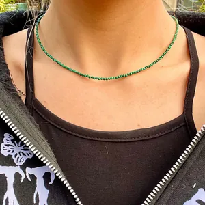 Close-up of a minimalist necklace featuring 2mm green malachite beads on a model's neck