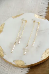 Detail of vintage long freshwater pearl tassel earrings with golden chains on marble tray
