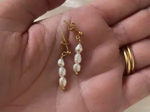 Dettaglio di perle barocche naturali su orecchini in titanio placcati oro 18K su mano