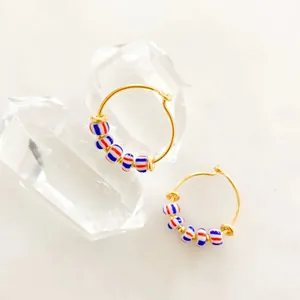 Detail of 18K gold-plated hoop earrings featuring red, white, and blue striped beads