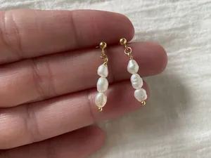 Dettaglio macro di tre perle barocche d'acqua dolce su orecchini a goccia in oro 18K