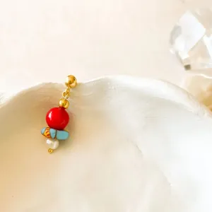 Detail view of handmade beaded earrings with red and blue beads on a ceramic edge