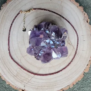 Detail of garnet beaded necklace with gold lobster clasp and heart charm on amethyst