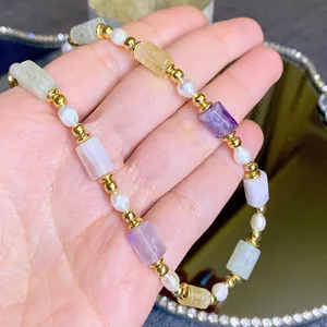 Collier vintage avec pierres naturelles colorées et perles d'eau douce tenu à la main