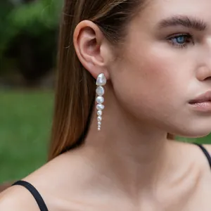 Orecchini pendenti con perle d'acqua dolce naturali bianche indossati da una modella