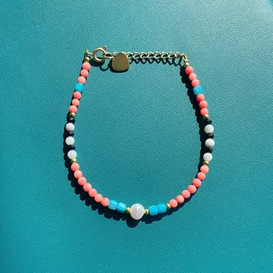 Bracelet en perles colorées avec pendentif coeur et fermoir doré sur cuir bleu canard