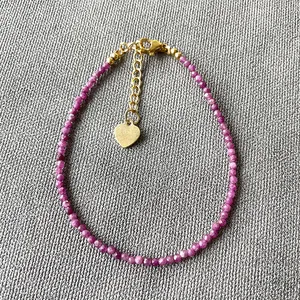 Bracelet fin fait main avec pierres magenta facettées et pendentif en cœur doré élégant