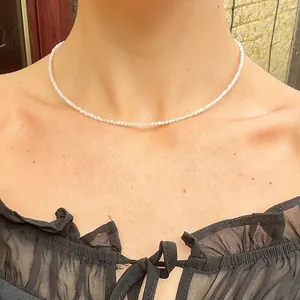Close-up of minimalist white faceted bead choker necklace worn on model neck
