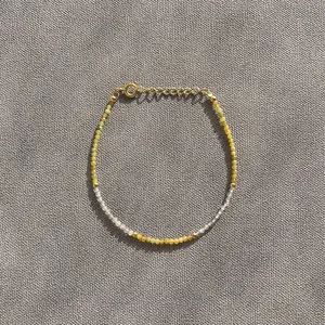 Minimalist beaded bracelet with natural stone beads and gold accents on grey fabric