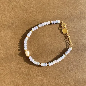 Détail de bracelet en perles bleues avec perle et pendentif cœur doré poli